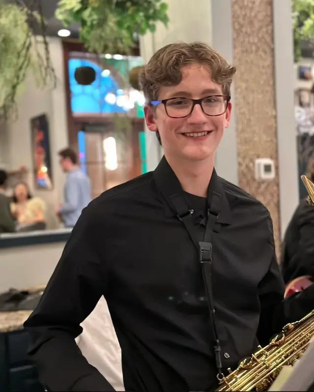 A saxophonist with The Scholars smiling before a restaurant performance
