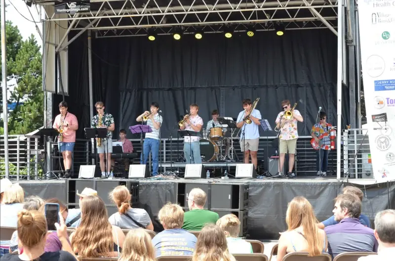 The Scholars playing a summer festival stage for a seated outdoor audience